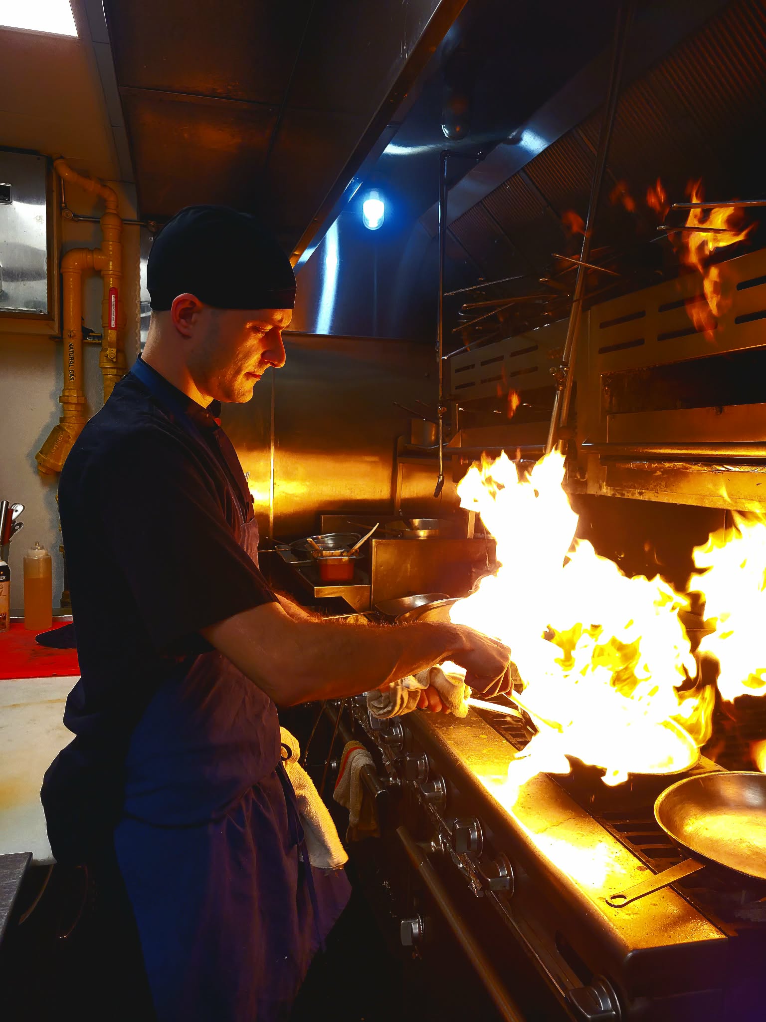 Chef JP cooking at a stove as flames rise from a pan.